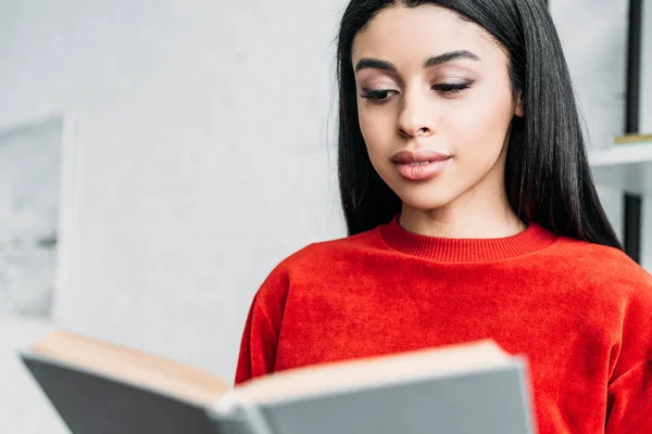 Pretty african american girl in red sweatshirt reading book — Stock Photo