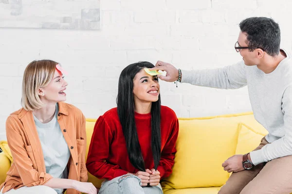 Multicultural friends having fun while fixing stickers on foreheads — Stock Photo