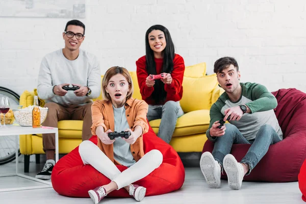 Fröhliche multikulturelle Freunde spielen Videospiel und genießen Getränke und Snacks auf der Heimparty — Stockfoto