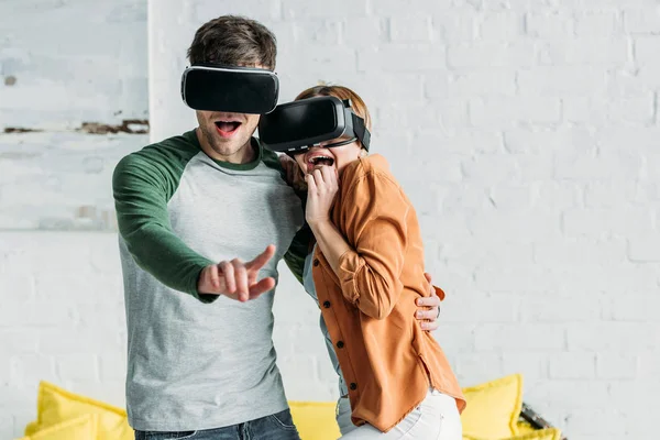 Amigos emocionados reaccionan emocionalmente mientras usan auriculares de realidad virtual - foto de stock