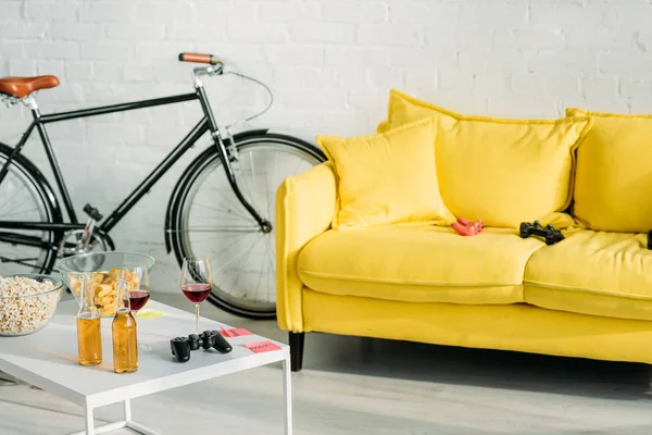 Soggiorno con comodo divano e tavolo giallo con bevande e snack — Foto stock