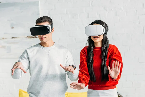 Casal interracial se divertindo usando fones de ouvido realidade virtual em casa — Fotografia de Stock