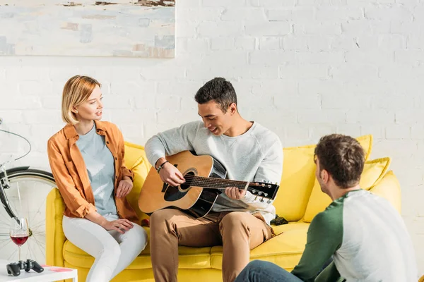 Young mixed race man playing guitar for multicultural friends — Stock Photo