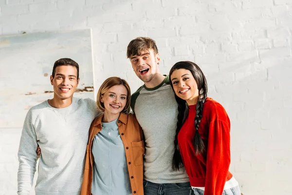 Lächelnde multiethnische Freunde, die zusammenstehen und in die Kamera schauen — Stockfoto