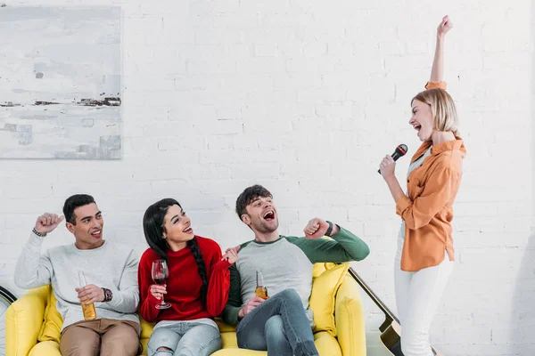 Multicultural friends having fun at home party while singing karaoke and enjoying drinks — Stock Photo