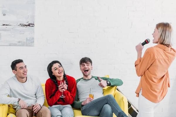 Amici multietnici divertirsi a casa festa mentre godendo bevande e cantando karaoke — Foto stock