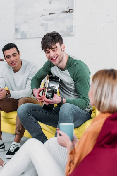 Beau jeune homme jouant de la guitare pour des amis multiethniques — Photo de stock