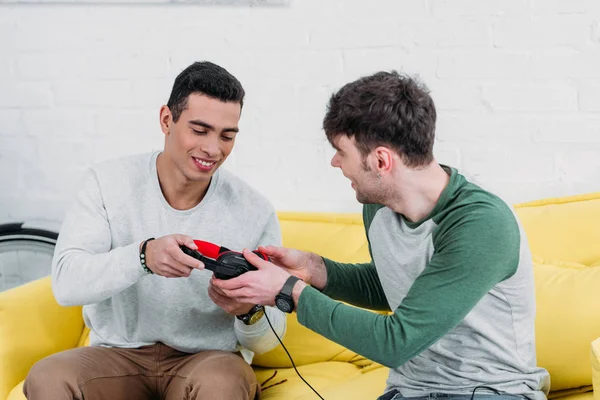 Young man giving headphones to mixed race friend — Stock Photo