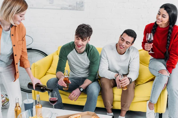 Multiethnic friends eating pizza and enjoying drinks at home party — Stock Photo