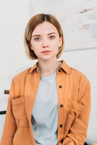Schöne junge Frau in orangefarbenem Hemd blickt in die Kamera — Stockfoto