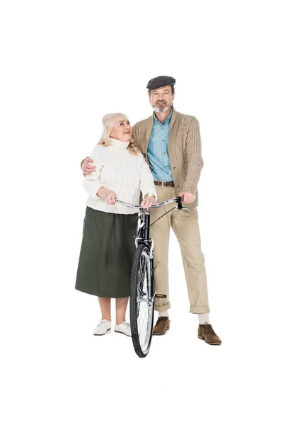 Alegre pensionista abrazando feliz esposa mientras sostiene bicicleta aislado en blanco - foto de stock