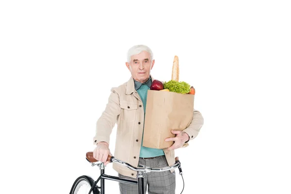 Hombre retirado sosteniendo bolsa de papel con productos y bicicleta aislada en blanco - foto de stock