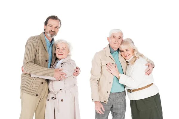 Cheerful retired couples hugging and smiling isolated on white — Stock Photo