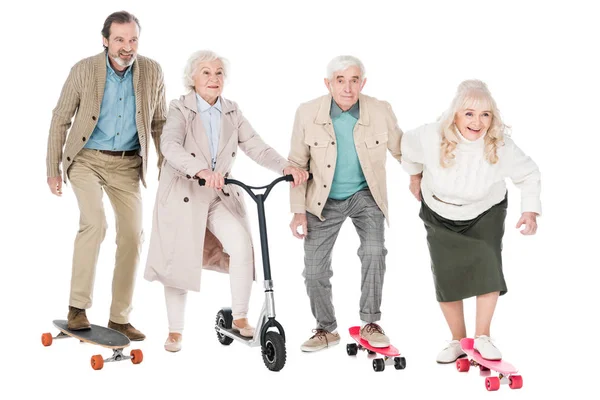 Jubilados alegres montar monopatines cerca de las mujeres en scooter aislado en blanco - foto de stock
