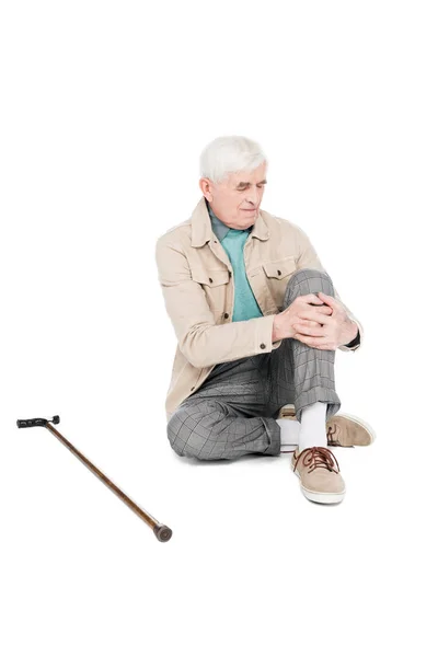 Пенсионер держит колено, испытывая боль от артрита, изолированную на белом — стоковое фото