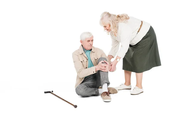 Retirado hombre sosteniendo la rodilla mientras tiene artritis dolor cerca de cuidar esposa aislado en blanco - foto de stock