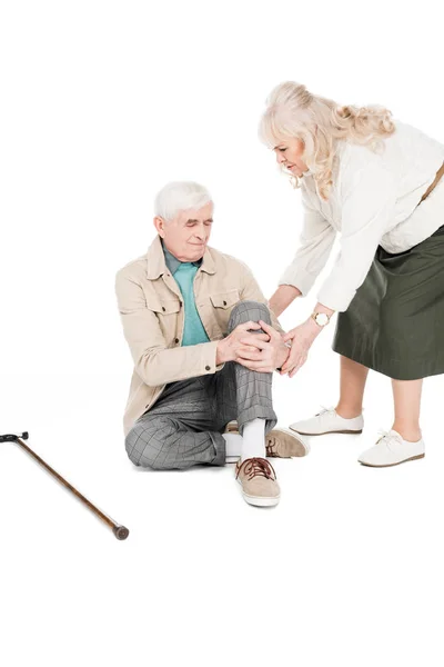 Senior man holding knee while having arthritis pain near caring wife isolated on white — Stock Photo