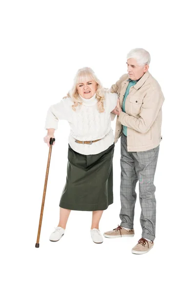 Seniorin hält sich zurück, während sie Arthritis-Schmerzen hat und mit fürsorglichem Ehemann isoliert auf weiß steht — Stockfoto