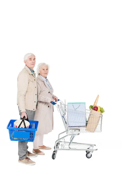 Senior husband and wife walking with shopping trolley and basket isolated on white — Stock Photo