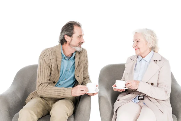 Felice marito in pensione guardando moglie in possesso di tazza mentre seduto in poltrona isolato su bianco — Foto stock