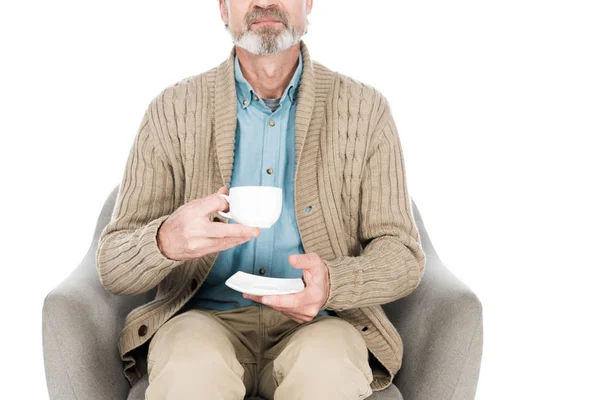 Обрезанный вид пожилой женщины, сидящей в кресле с чашкой чая изолированы на белом — стоковое фото