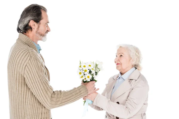 Веселий старший чоловік дарує квіти щасливій жінці ізольовані на білому — стокове фото