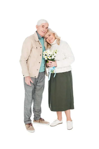 Homem sênior alegre de pé com esposa feliz segurando flores isoladas no branco — Fotografia de Stock