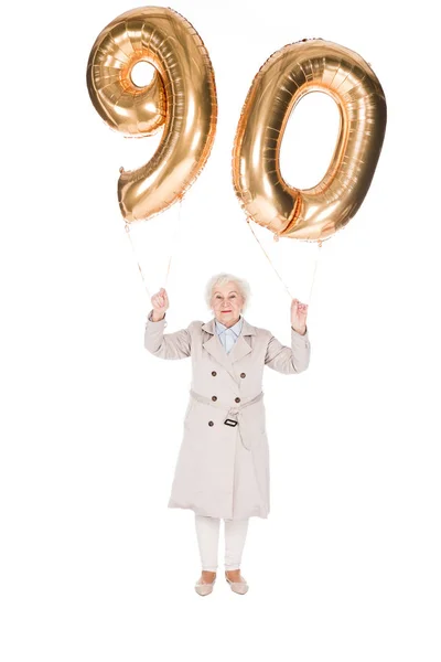 Feliz anciana sosteniendo 90 globos dorados aislados en blanco - foto de stock
