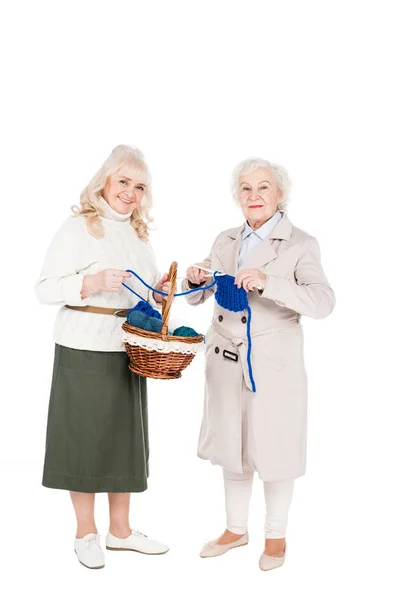Gai retraité femme tricot près ami tenue panier isolé sur blanc — Photo de stock