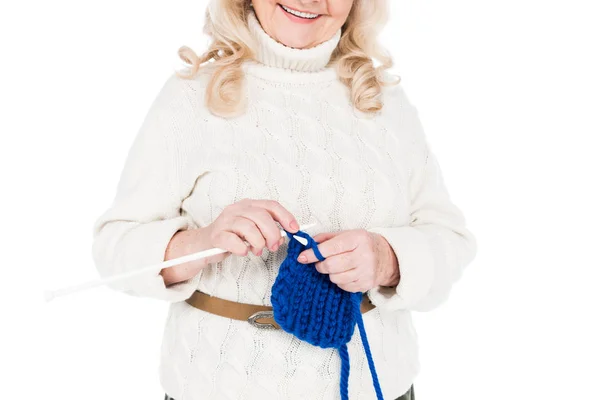 Abgeschnittene Ansicht einer glücklichen Seniorin, die isoliert auf Weiß steht und strickt — Stockfoto