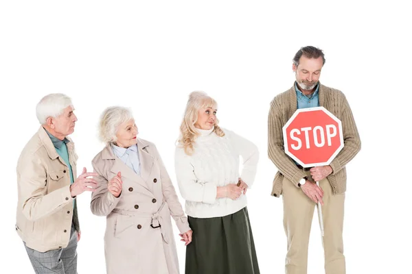 Jubilados mirando a un hombre mayor sosteniendo un letrero de stop en manos aisladas en blanco - foto de stock