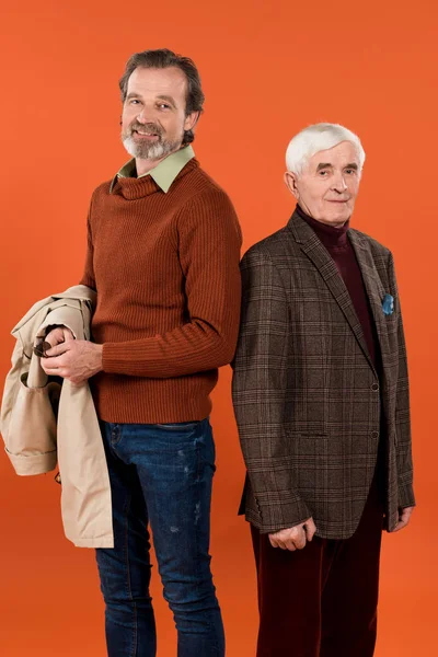 Модні веселі чоловіки на пенсії стоять ізольовані на помаранчевому — стокове фото