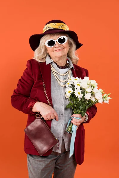 Trendige Seniorin mit Sonnenbrille und Hut mit Blumen in Orange — Stockfoto