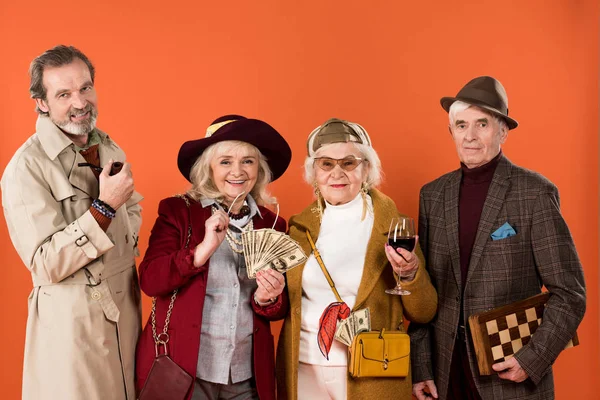 Cheerful retired man holding smoking pipe near senior friends isolated on orange — Stock Photo