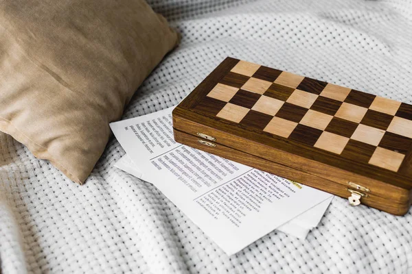 Tabuleiro de xadrez de madeira perto de jornal no sofá — Fotografia de Stock