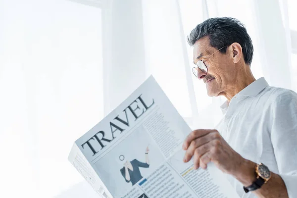 Homem sênior feliz lendo jornal de viagem em casa — Fotografia de Stock