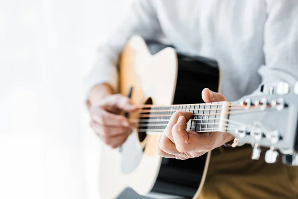 Обрезанный вид пожилого человека, играющего на акустической гитаре дома — стоковое фото