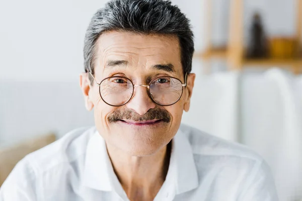 Щасливий старший чоловік в окулярах посміхається вдома — стокове фото