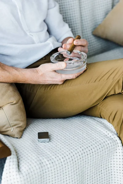 Cropped view of senior man holding sigar and ashtray in hands — Stock Photo