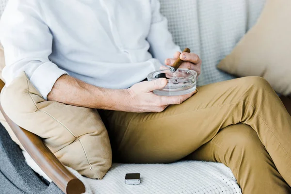 Cropped view of pensioner holding sigar and ashtray in hands — Stock Photo