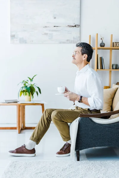 Aposentado homem com bigode segurando xícara com café em casa — Fotografia de Stock