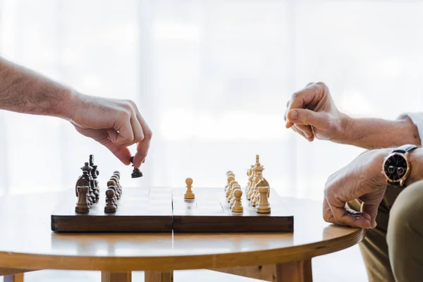 Vista recortada de las personas mayores jugando ajedrez en casa - foto de stock