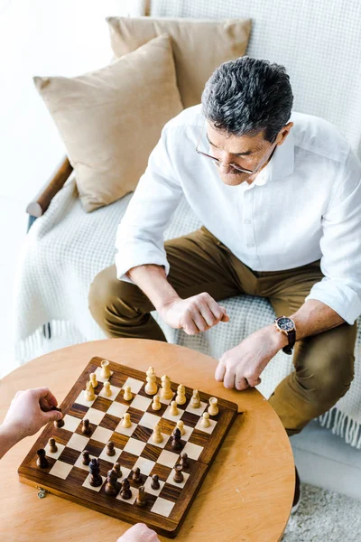 Вид сверху на пенсионеров, играющих в шахматы дома — стоковое фото