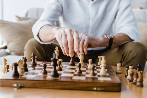 Visão cortada do homem aposentado com jogar xadrez em casa — Fotografia de Stock