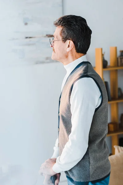 Senior man with grey hair standing in living room — Stock Photo