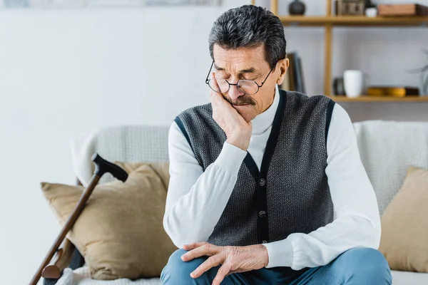 Pensionato seduto vicino bastone da passeggio con gli occhi chiusi — Foto stock