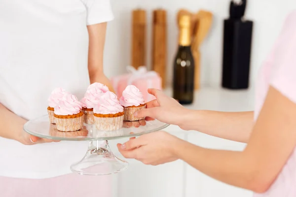 Cropped view of girl taking pink cupcake from glass stand — Stock Photo