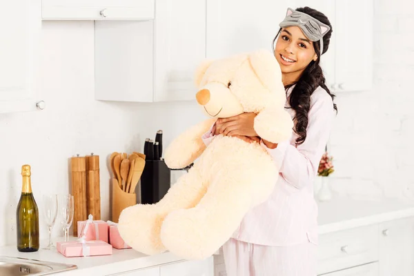 Beautiful african american girl holding teddy bear during pajama party at home — Stock Photo