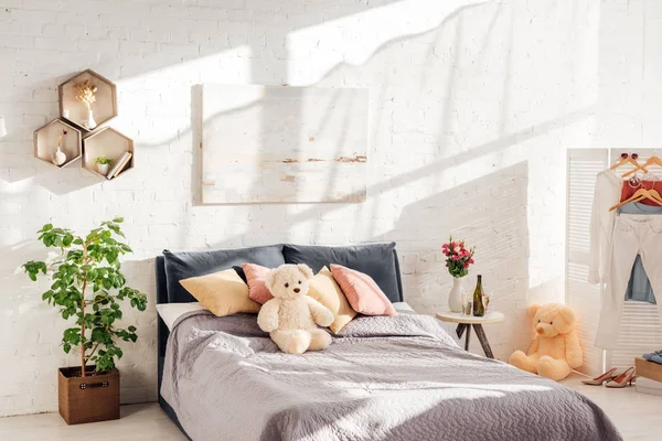 Modern interior design of bedroom with teddy bear toys, pillows, plants and bed — Stock Photo