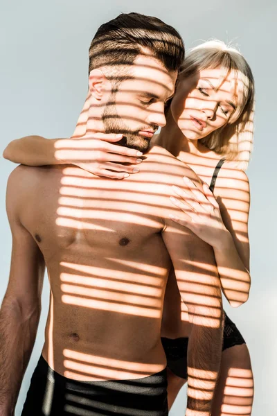 Sensual girlfriend hugging handsome shirtless boyfriend isolated on grey with shadows — Stock Photo